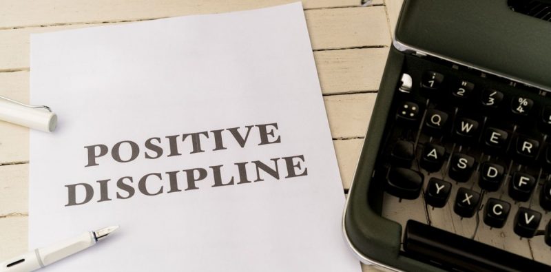 a piece of paper that says positive discipline next to a typewriter